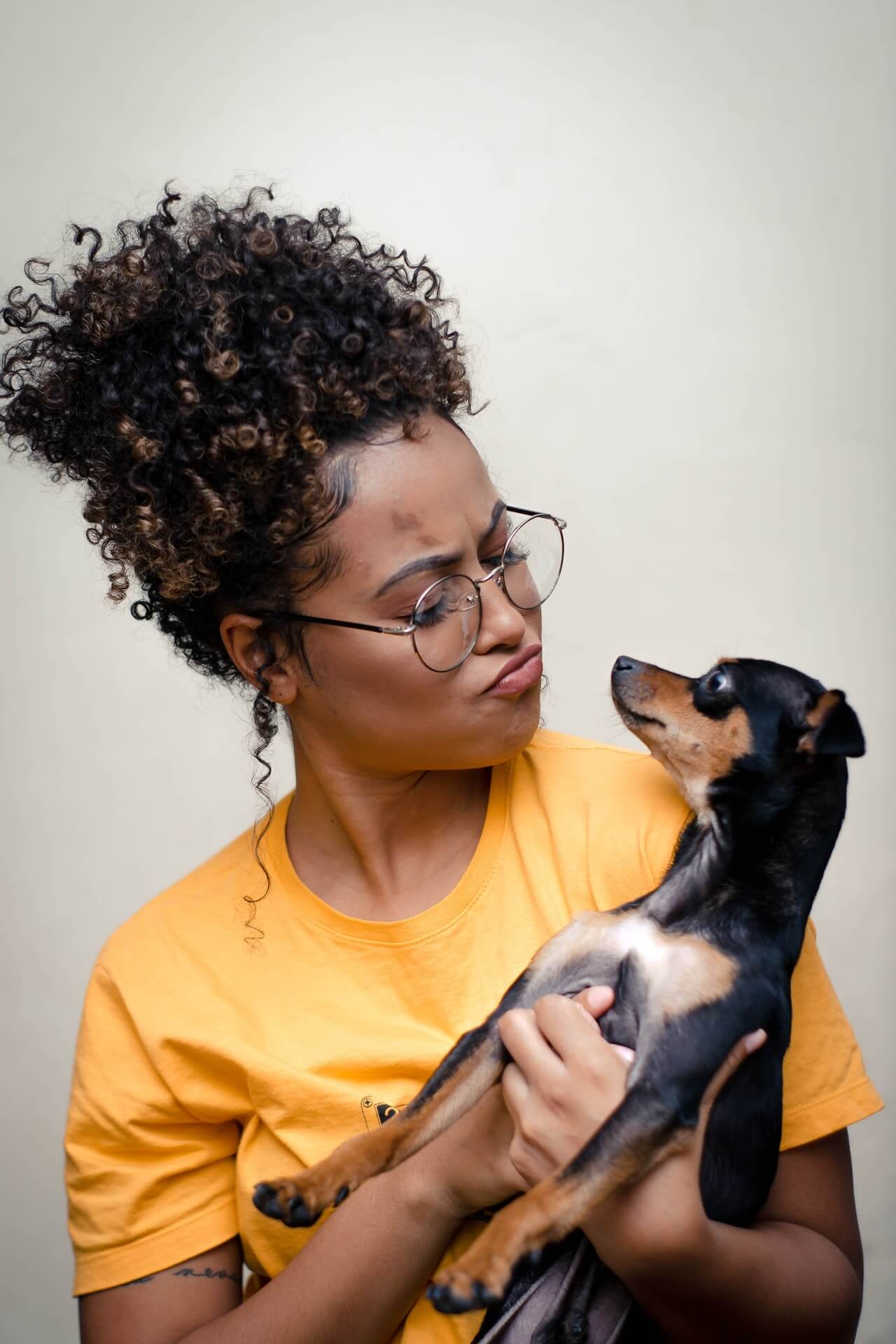 woman-holding-short-coated-black-and-brown-puppy-3190736